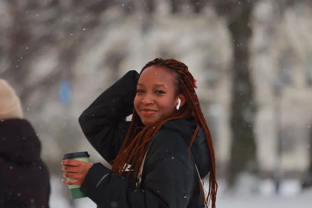 A woman wearing ear buds to listen to music in Winter.