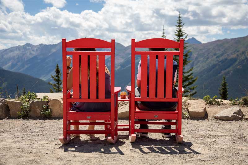 2 People Sitting In Red Adirondack Chairs. Aspen, Colorado